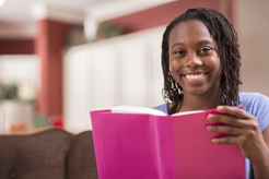 Girl holding a book and smiling at the camera.