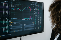 Photo of woman looking at investing and trading reports on a monitor.
