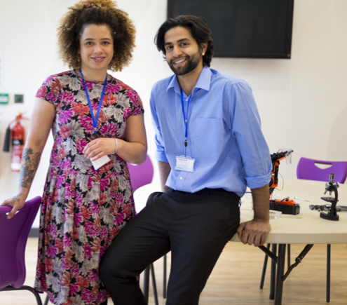 Two teaches in a classroom smiling at the camera.